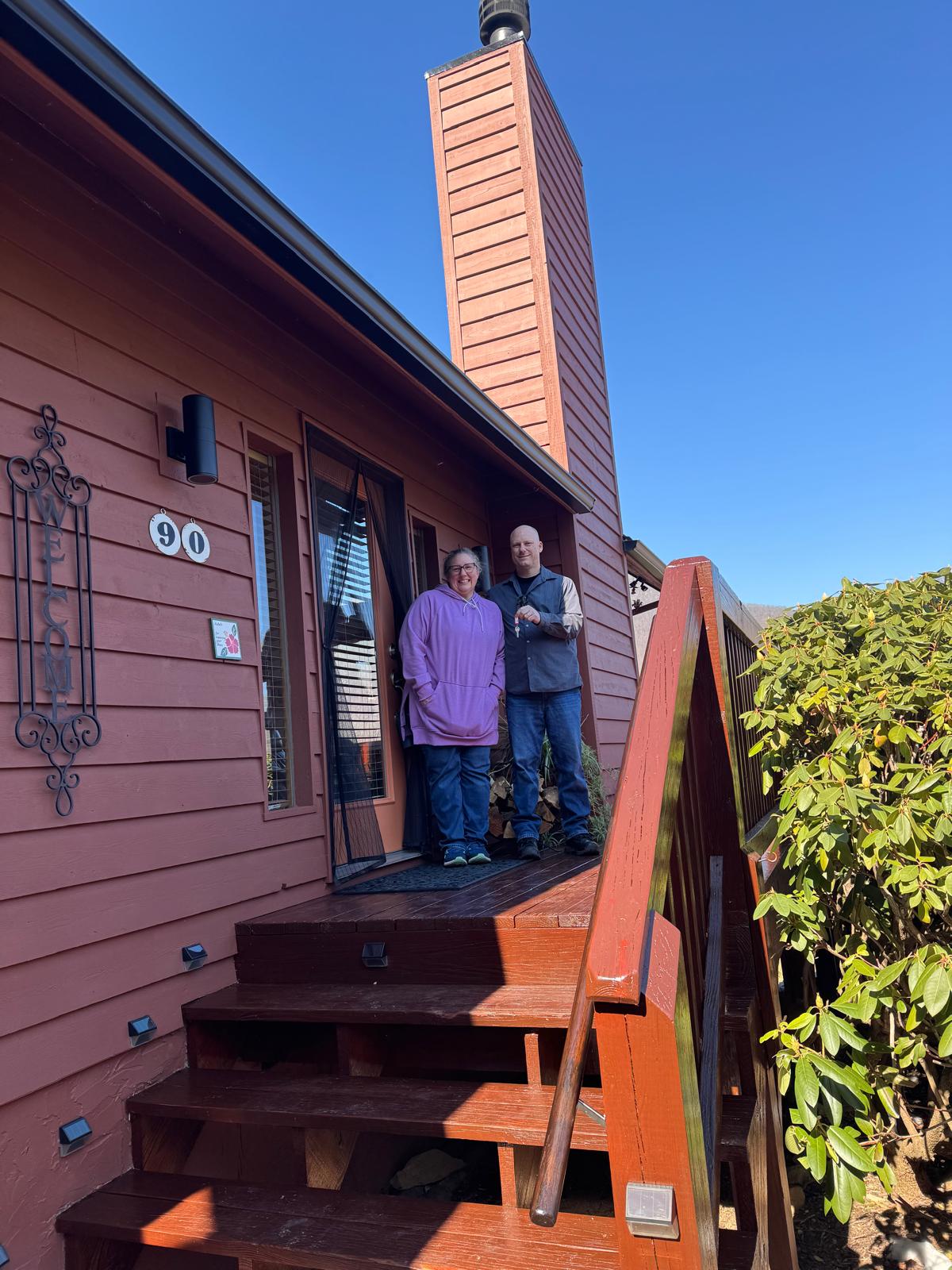 Couple at front porch of home with keys on closing day